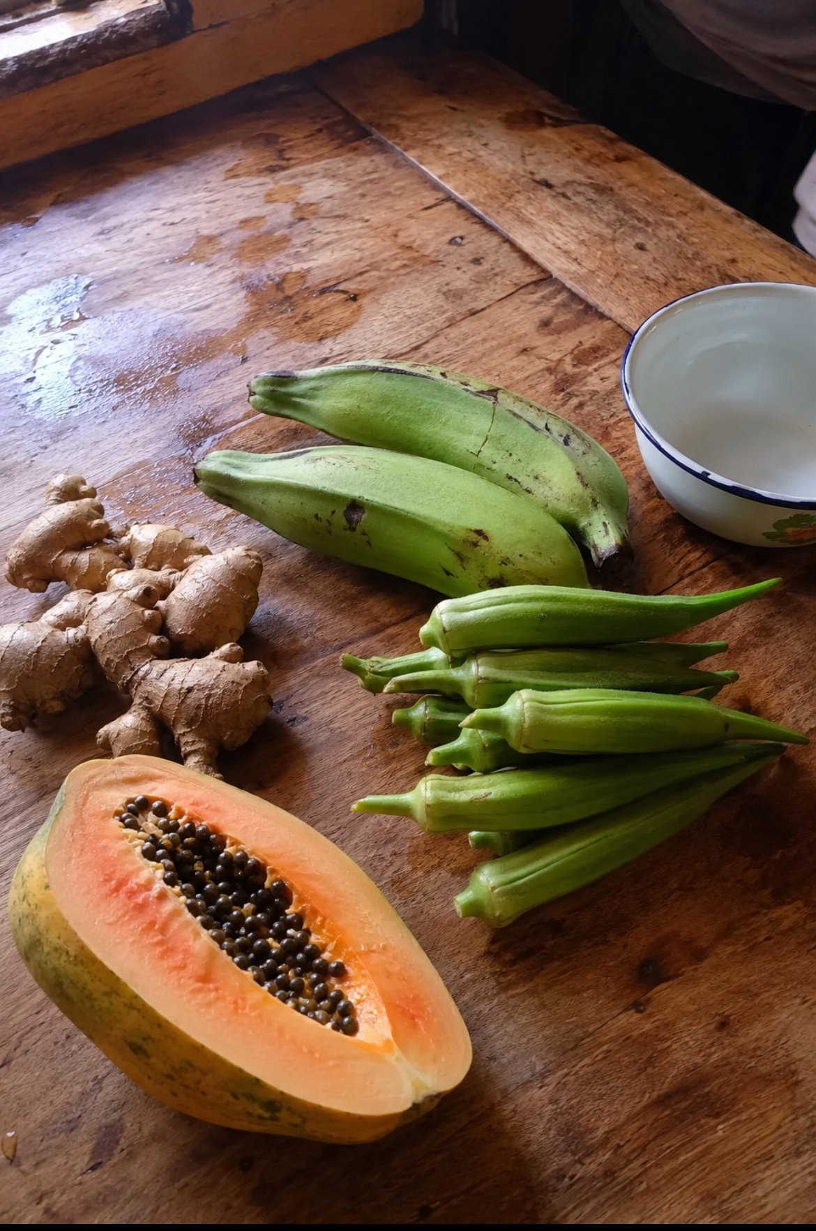 Ginger, unripe plantain, okra and pawpaw on a kitchen table